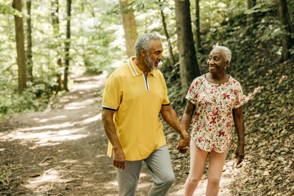 Retired couple walking hand in hand on a forest trail