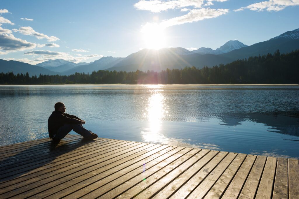 Person sitting alone on a dock at sunrise, thinking through retirement without savings